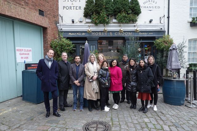 A group of guests on a private walk gather on a cobbled Belgravia mews outside the Horse & Groom pub