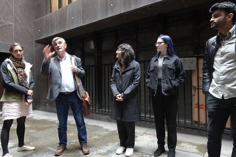 A guide tells a story to a group of young professionals in a narrow City of London alleyway