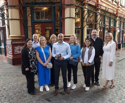 Smiling colleagues gather for a team photo on the cobbles of Leadenhall Market during a staff wellbeing day