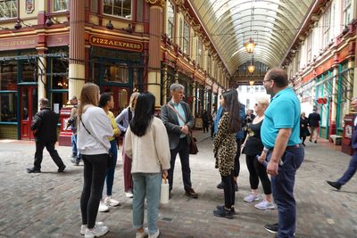Colleagues chat as they gather around their guide on the cobbles of Leadenhall Market during a lunchtime wellbeing walk